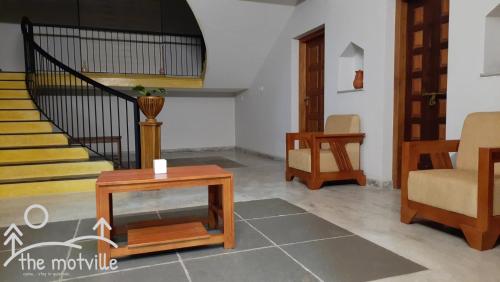 a living room with a table and a staircase at the motville in Pulpally