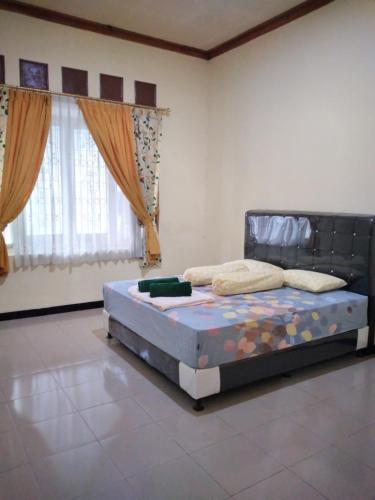 - une chambre avec un lit dans une pièce dotée de fenêtres dans l'établissement RUMAH PAKSI HOMESTAY, à Tanjungkarang