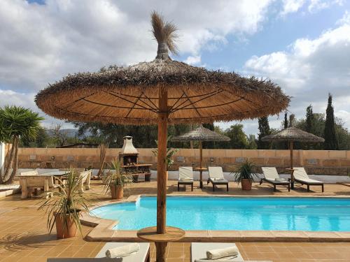 a large straw umbrella sitting next to a swimming pool at Eco Finca Sa Font Blava in Llucmajor