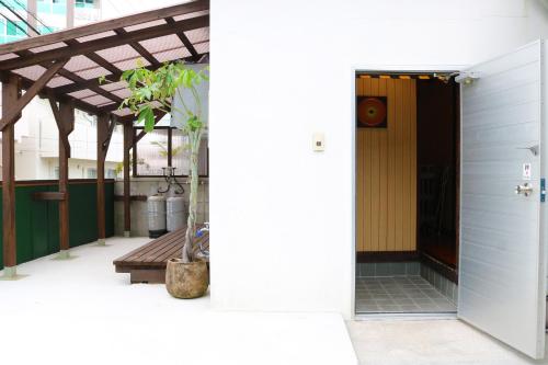 那霸的住宿－Okinawa Naha JinJin -沖縄伝統体験型宿じんじん-，通往带长凳的大楼的敞开的门