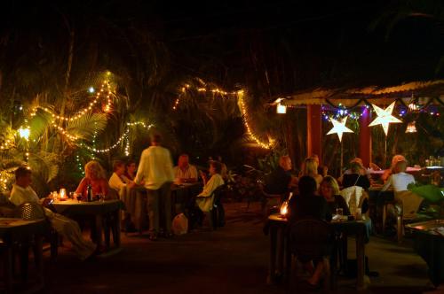 a group of people sitting at tables in a restaurant at night at Palm Grove Cottages - Leisure Resort in Benaulim