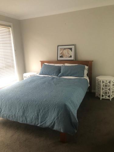 a bedroom with a large bed with a blue comforter at Brand new 4br get away 5min to albury city in Lavington