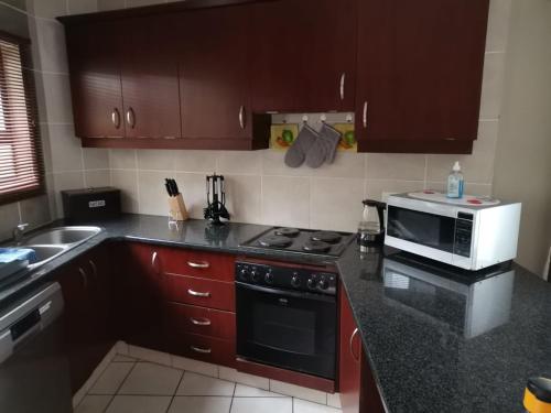 a kitchen with a stove and a microwave at 24 Topanga in Uvongo Beach