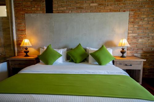 a large bed with green pillows and two lamps at The Plains Green in Ambawela