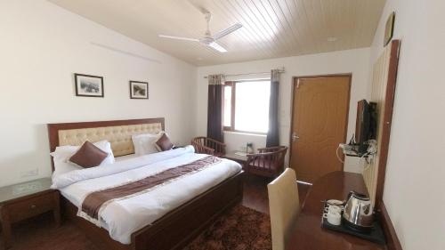 sypialnia z łóżkiem, biurkiem i telewizorem w obiekcie Hotel Sunny Cot Mussoorie Mallroad w mieście Mussoorie