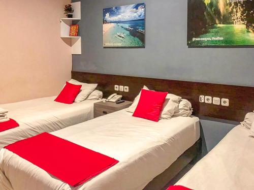 two beds in a room with red and white sheets at Audah Syariah Residence Mitra RedDoorz in Surabaya