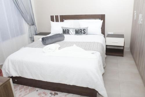 Royal Luxury Hotels and Apartments في Kitwe: غرفة نوم بسرير كبير عليها شراشف ووسائد بيضاء