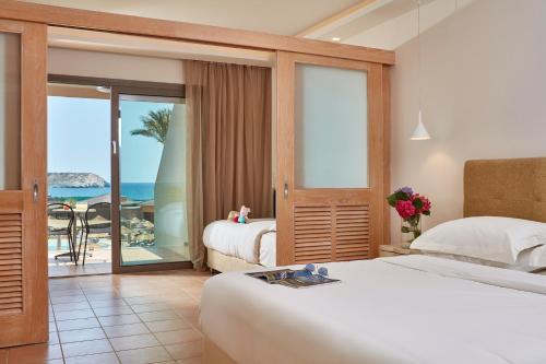 a hotel room with two beds and a view of the ocean at Atlantica Aegean Blue in Kolimbia