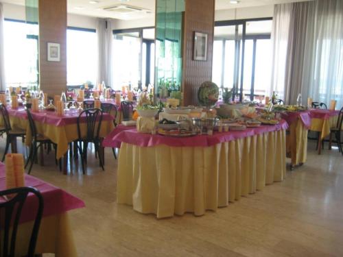 una sala da pranzo con tavoli con tovaglia rosa e gialla di Hotel Suprem a Rimini