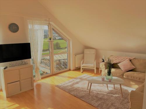 - un salon avec un canapé, une télévision et une table dans l'établissement Ferienwohnung Sonnenblick in Losheim am See, à Losheim