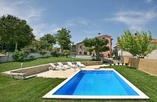 a swimming pool in a yard with chairs and a house at Guest House Valentino in Motovun