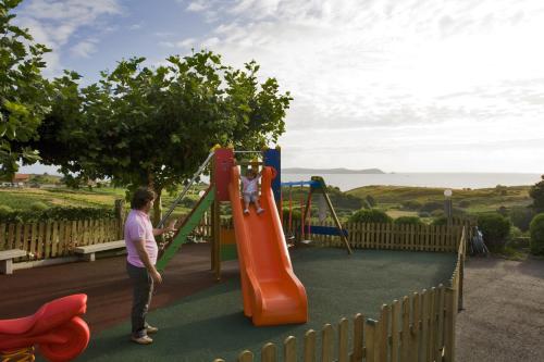 a woman standing in front of a playground at Hotel Oca Vermar in Aios