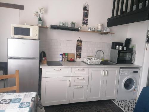 a kitchen with a white refrigerator and a dishwasher at Le charme du bois in Écharcon