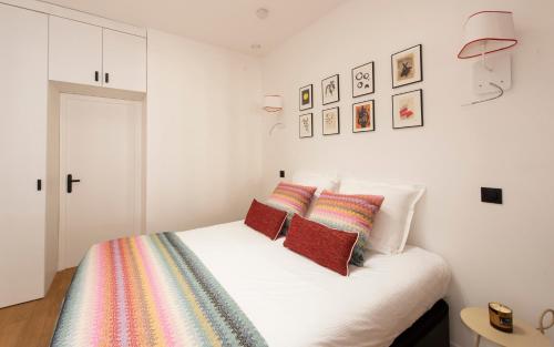 a white bedroom with a bed with colorful pillows at Andy in Paris