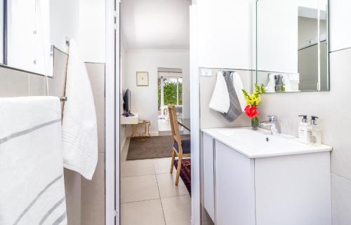 a white bathroom with a sink and a mirror at Bleu Cobalt Cottage in Franschhoek