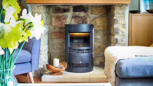 a fireplace in a living room with a stone wall at Woodbine Cottage in Bourton on the Water