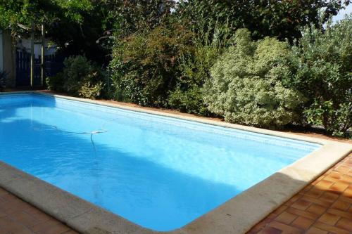 una gran piscina azul con árboles en el fondo en Gîte de charme au coeur du vignoble de St Emilion, en Génissac