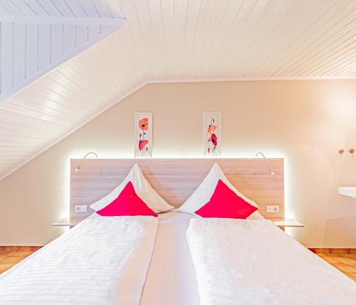 1 dormitorio con 1 cama blanca grande con almohadas rojas en Johannishof Wein-Café & Gästehaus, en Mesenich