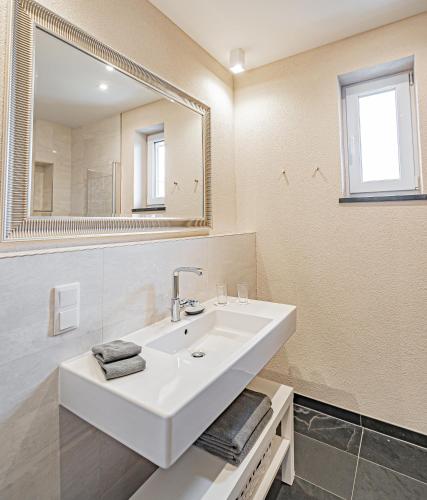 a white bathroom with a sink and a mirror at Johannishof Wein-Café & Gästehaus in Mesenich