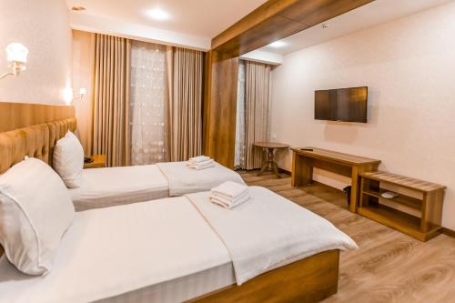 a hotel room with two beds and a television at OydinPlaza Hotel in Namangan