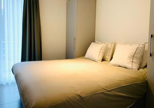 1 dormitorio con 1 cama grande con almohadas blancas en Even Aan Zee - Dukdalf, en Nieuwpoort