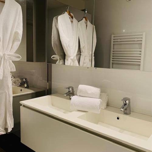 uma casa de banho com um lavatório e um espelho com toalhas em Even Aan Zee - Dukdalf em Nieuwpoort