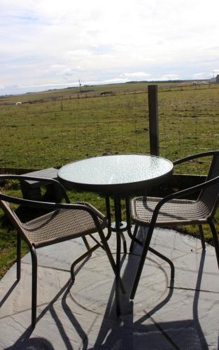 a table and two chairs with a table and a field at Hillside Camping Pods and Shepherd's Hut in Wick
