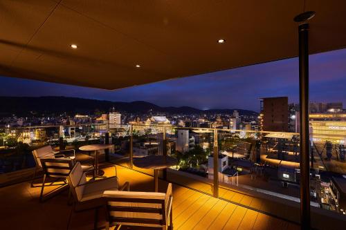 a balcony with a view of a city at night at The Gate Hotel Kyoto Takasegawa by Hulic in Kyoto