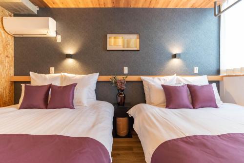 2 camas en una habitación de hotel con almohadas moradas y blancas en Alla Scuderia Bijou Suites, en Osaka