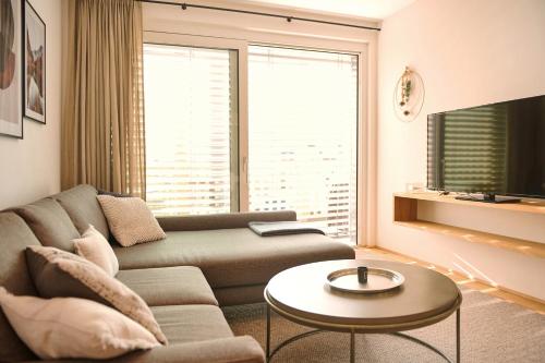 a living room with a couch and a table at die Tauplitz Lodges - Wasserfall Lodge C4 by AA Holiday Homes in Tauplitz
