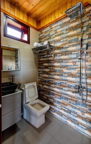 a bathroom with a toilet and a stone wall at Art Villa Hoi An in Hoi An