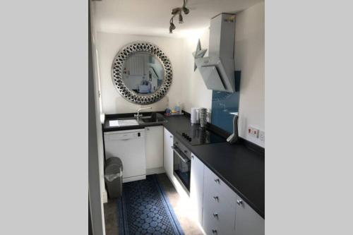 a kitchen with black counter tops and a mirror at On The Harbour - unrivalled views of Amble's harbour and estuary in Amble