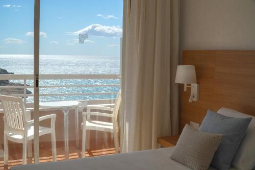 Hotel Cala Font في سالو: غرفة نوم مع سرير وإطلالة على المحيط