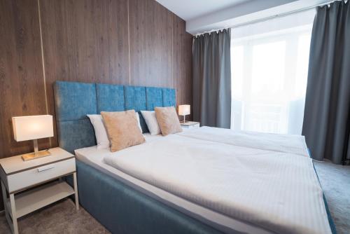 a bedroom with a large bed with a blue headboard at Cassian Inn in Partizánske
