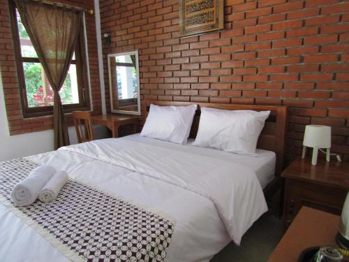 a bedroom with a white bed and a brick wall at Penginapan Udin Syariah Bukit Rhema in Magelang