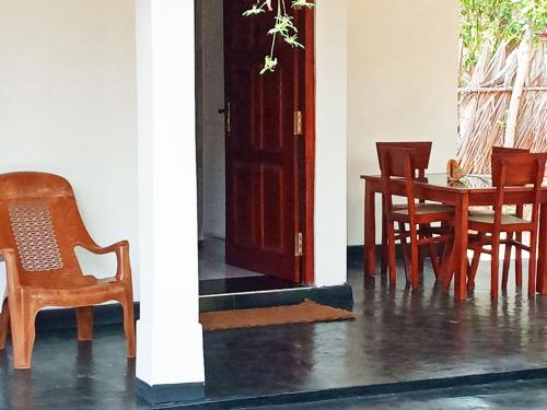 um quarto com uma mesa e cadeiras e uma porta em Sulashika Beach House em Kandakuli