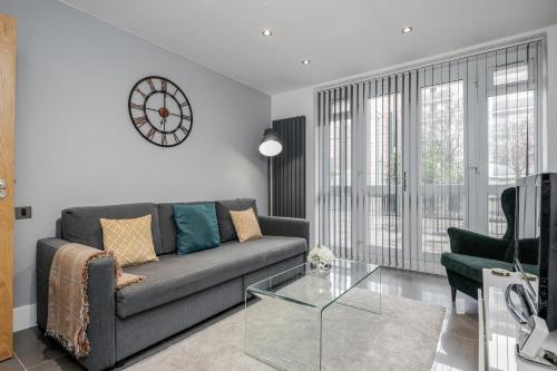 a living room with a couch and a clock on the wall at Luxury Chic Apartment near Canary Wharf, Excel, O2 & Stratford in London