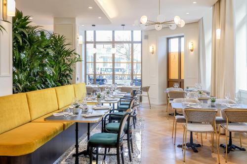 a restaurant with tables and chairs and a yellow couch at Hotel des Vosges BW Premier Collection in Strasbourg