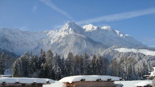 a snow covered mountain in the distance with two benches at Hagerhof in Walchsee