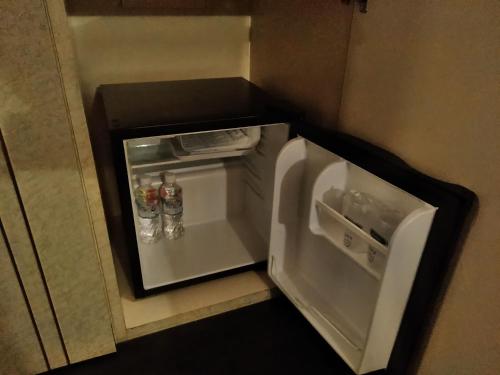 a small white refrigerator with its door open at Hotel Liberty Kochi (Adult Only) in Kochi