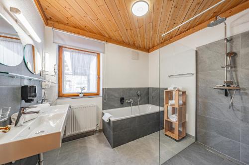 uma casa de banho com uma banheira, um lavatório e um chuveiro em Almkönig em Maria Alm am Steinernen Meer