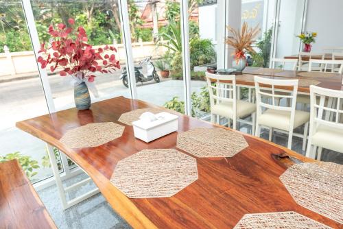una mesa de madera con un jarrón de flores. en Siri Ville Hotel, en Sisaket