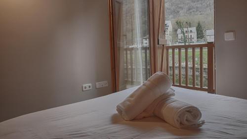 a rolled up towel sitting on a bed with a window at Saplan Real Estate PORTET in Les