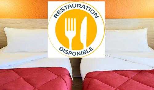 a hotel room with a fork and knife sign on the bed at Premiere Classe Lille Sud - Seclin in Seclin