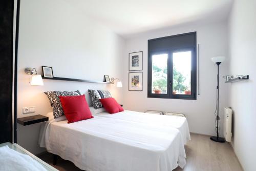 1 dormitorio con 1 cama blanca grande con almohadas rojas en La Conca, encantador apartamento para 2 pax E34026, en S'Agaró