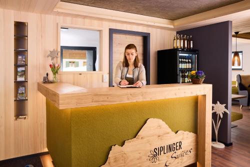 a woman is standing behind a counter in a room at Siplinger Suites - Ferienwohnungen - Sauna und Fitness in Balderschwang