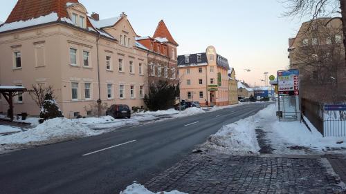 an empty street with snow on the sides of buildings at Hotel Weberhof in Zittau