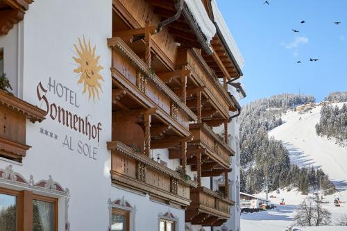 a building with wooden balconies on a ski slope at Hotel Al Sonnenhof in San Vigilio Di Marebbe