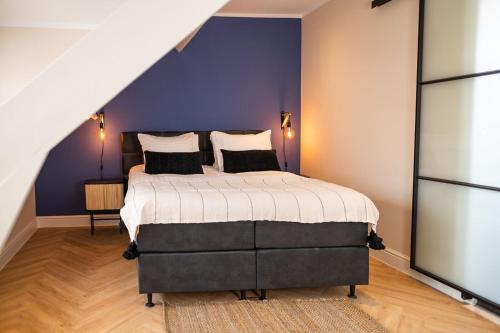 a bedroom with a large bed with a purple wall at Bed en Baguette in Burgh Haamstede