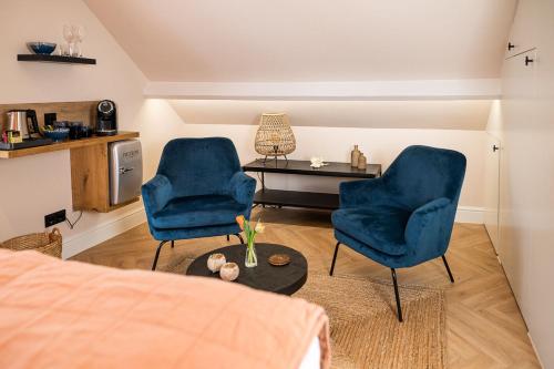 a living room with two blue chairs and a table at Bed en Baguette in Burgh Haamstede